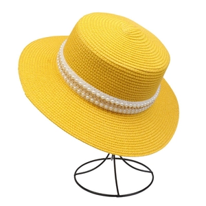 Close-up of yellow straw sun hat with elegant pearl and gold chain decorative band