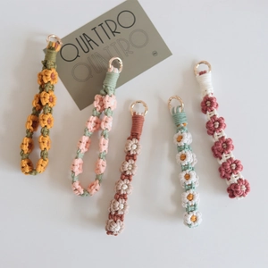 Detailed view of handmade woven daisy flower keychains in five different color combinations