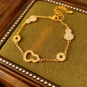 Detail of 24k gold-plated gourd and coin bracelet with white zircon pave on green velvet