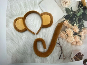 Detailed plush brown monkey ears headband and long tail set on soft fur background