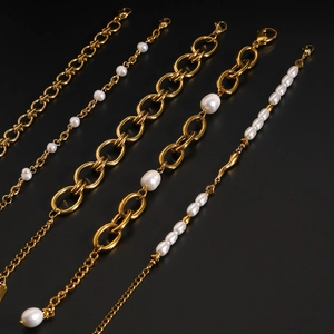 Close-up of assorted gold-plated stainless steel bracelets with freshwater pearls on black