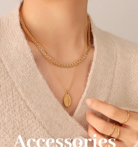 Detail of 18K gold-plated oval pendant and braided chain necklace on knitwear