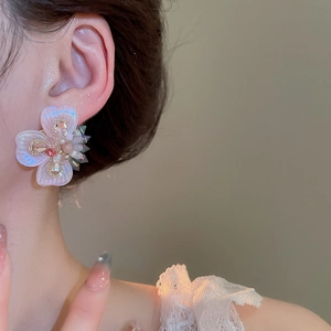 Detail of flower stud earrings with iridescent petals and sparkling pink crystal center