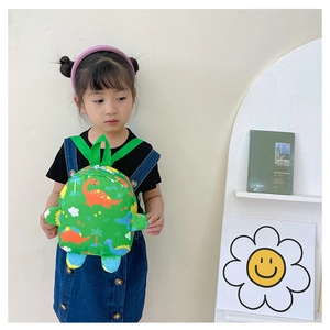Detail of cute green dinosaur kids backpack with 3D limb features on a child model