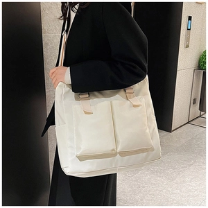 Detailed shot of large white nylon shoulder bag with adjustable beige strap on model
