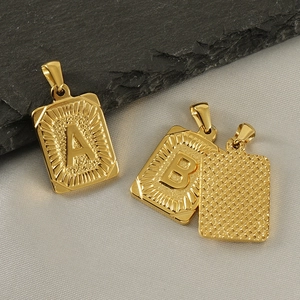 Detail view of gold 18K titanium steel rectangular pendants with letters A and B