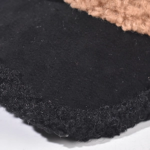Macro detail showing the soft black plush and beige lamb wool texture on a kids cap.