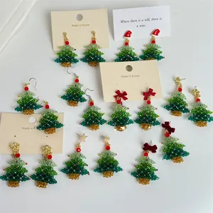Detailed view of handmade beaded Christmas tree earrings with festive red bows