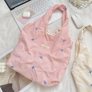 Close-up of checkered canvas tote bag with colorful butterfly embroidery and daily essentials