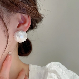 Close-up of white oversized pearl studs with unique wrinkled texture for elegant women
