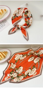 Detailed view of pleated silk scarf featuring orange floral patterns and accordion folds