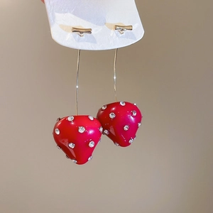Macro view of red resin strawberry earrings with sparkling rhinestones and gold hooks