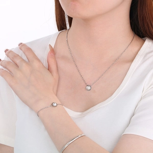 Détail de l'ensemble collier et bracelet en perles argentées porté par un mannequin
