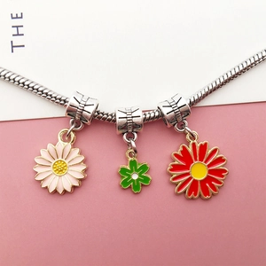 Detail of DIY silver snake chain necklace featuring enamel daisy and flower pendants