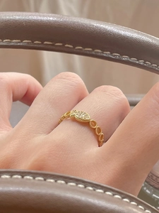 Close-up of gold hollow ring with sparkling zircons worn while holding a leather bag