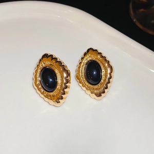 Macro detail of retro gold flower earrings with oval black onyx gemstone inlay