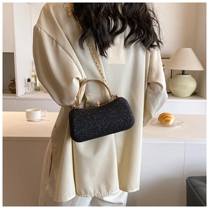 Close-up of black glitter evening clutch with gold metal handle and chain strap