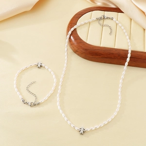 Detail view of pearl beaded jewelry set featuring girl pendants on satin background