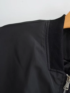 Detail einer schwarzen Bomberjacke mit Rippkragen und silbernem Metallreißverschluss