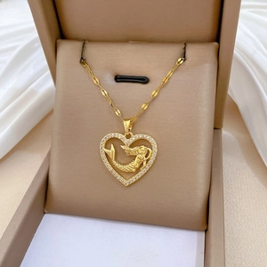 Detailed close-up of a gold heart mermaid pendant with pavé diamonds on a silk cushion