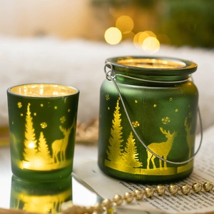 Photophores de Noël en verre vert givré avec motifs de rennes et sapins, ambiance chaude