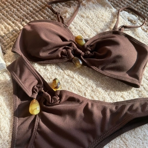 Detail showing brown ribbed bikini fabric with amber resin stone decorations on towel