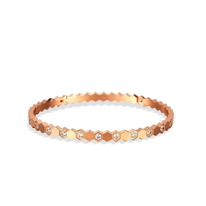 Rose gold honeycomb bangle with geometric hexagonal design and inset crystals on a white base