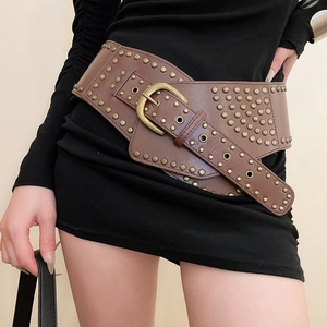 Detail of a wide vintage dark brown leather belt with brass rivets on a black dress