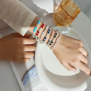 Close-up of elegant bracelets featuring colorful rectangular zircon stones on a white tray