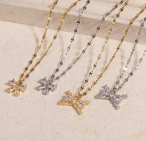 Détail de pendentifs papillons dorés et argentés avec zircons sur un tissu beige