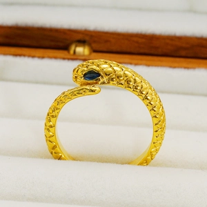 Golden stainless steel snake ring with blue gemstone eyes displayed in a jewelry box