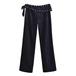Women's black flare pants with metallic studs and side lace-up detail on plain white background