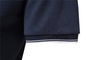 Detail of dark blue pique cotton polo shirt sleeve with black and white striped cuff