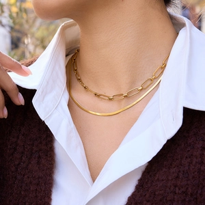 Detail of layered gold stainless steel necklace with flat snake and paperclip chains