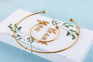 Detail view of a gold-plated stainless steel collar and bracelet set with ball ends on a card