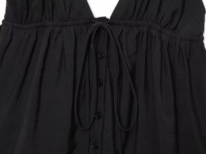 Détail du caraco noir montrant le tissu tissé avec boutons et design à lacets