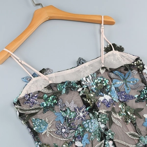 Détail de la broderie florale complexe et des paillettes colorées sur robe en dentelle