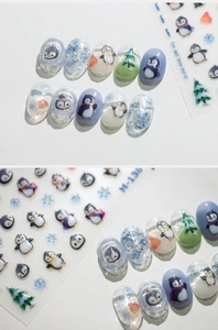 Détail de stickers à ongles pingouin et flocon M-136 sur des ongles en gel bleu