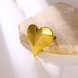 Modern gold-plated stainless steel ring with faceted heart design on a stone base