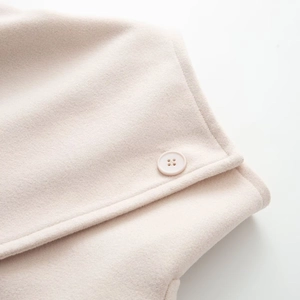 Gros plan macro sur la texture laine beige et le bouton assorti d'un manteau d'hiver