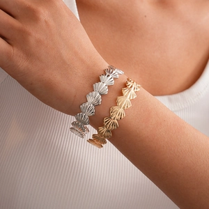 Macro detail of gold and silver shell link bracelets showing fine radiant scallop texture