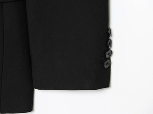 Vue détaillée du bas de manche de costume avec quatre boutons noirs et tissu de qualité