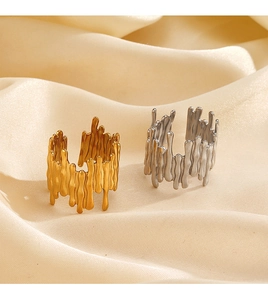 Detailed close-up of gold and silver lava-textured adjustable rings on beige silk fabric