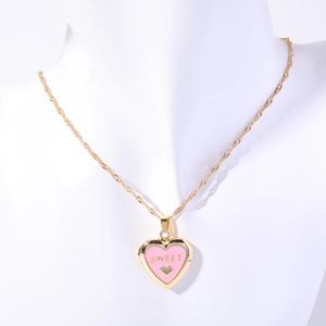 Close-up of gold heart locket necklace with pink enamel and Sweet engraving on white model