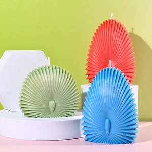 Dettaglio di candele colorate a forma di conchiglia con trame a coste su basi geometriche