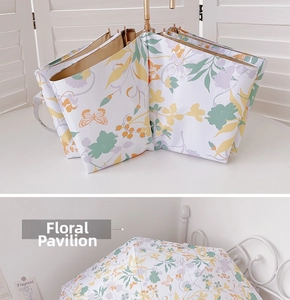 Close-up of floral butterfly pattern on white fabric with elegant golden umbrella handle