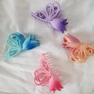 Detail of matte gradient tulip and butterfly hair claws on white fabric texture
