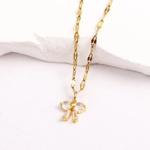 Détail d'un pendentif papillon doré serti de zircons sur une chaîne à maillons plats