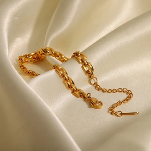 Detailed macro view of 18K gold-plated stainless steel chain on ivory silk fabric