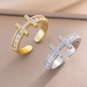 Dettaglio di anelli a croce in oro e argento con pavé di zirconi cubici lucenti